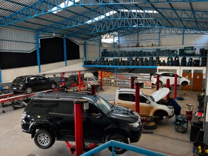 Vista interna da oficina com vários elevadores e veículos em atendimento