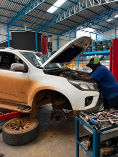 Mecânico realizando manutenção em uma pick-up no box da oficina